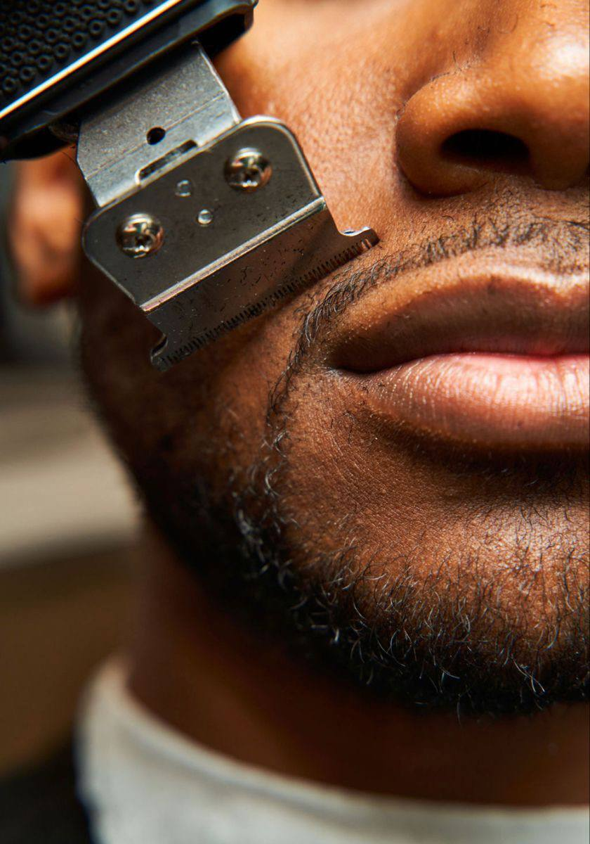 Stylist shaping a client's beard with precision clippers